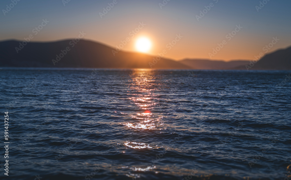 Beautiful sea sunset. A ball of sun setting in the hills. Focus on the surface of the water Beautiful sea sunset. A ball of sun setting in the hills. Focus on the surface of the water
