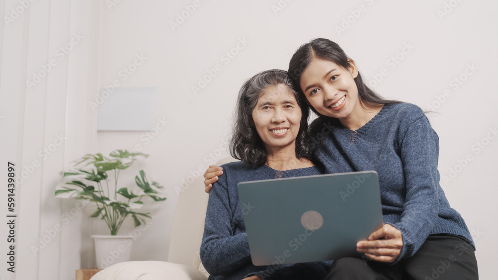 Using laptop, online shopping, Mother's day concept, young adult female daughter congratulate excited asian elderly mother at sofa with birthday anniversary, two generations family photo, real people. Using laptop, online shopping, Mother's day concept, young adult female daughter congratulate excited asian elderly mother at sofa with birthday anniversary, two generations family photo, real people.