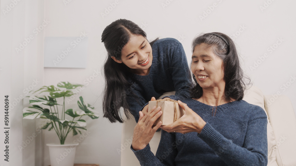 Mother's day concept, young adult female daughter congratulate excited asian elderly mother at sofa with birthday anniversary, two generations family photo, real people. Mother's day concept, young adult female daughter congratulate excited asian elderly mother at sofa with birthday anniversary, two generations family photo, real people.