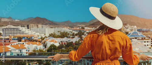 woman standing on balcony and enjoying view to the Playa de las Americas holiday resort skyline in Tenerife. banner with copy space