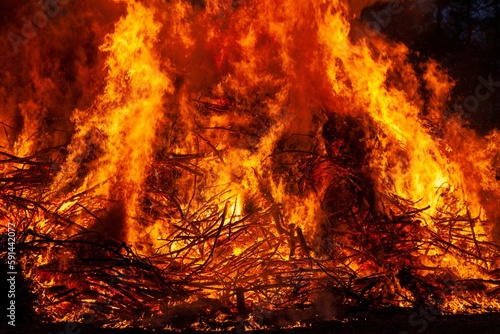 a big pile of sticks in a field with flames on top