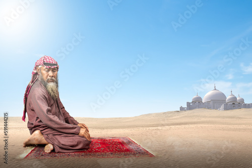 Muslim man with a beard wearing keffiyeh with agal in praying position (salat) on the prayer rug