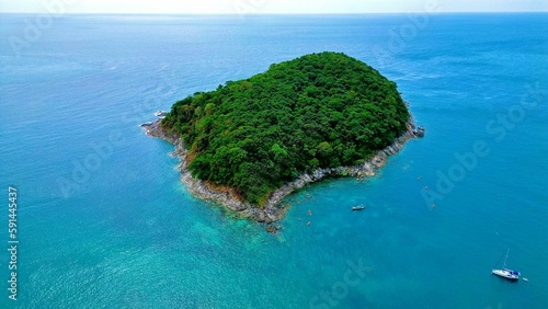 Aerial view of a tropical island surrounded by lush green vegetation and crystal blue water