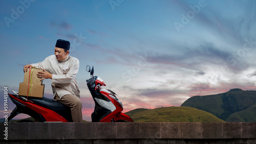 Asian Muslim man tying box on motorcycle prepare for mudik © Leo Lintang