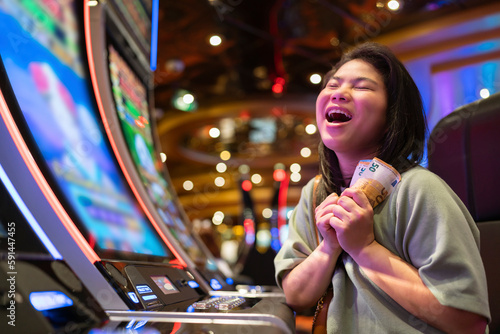 exited asia female woman slot machine gambling cheerful smile hand pressing bet button in casino club entertainment concept,exited asian woman hand play slot machine in casino hotel © whyframeshot