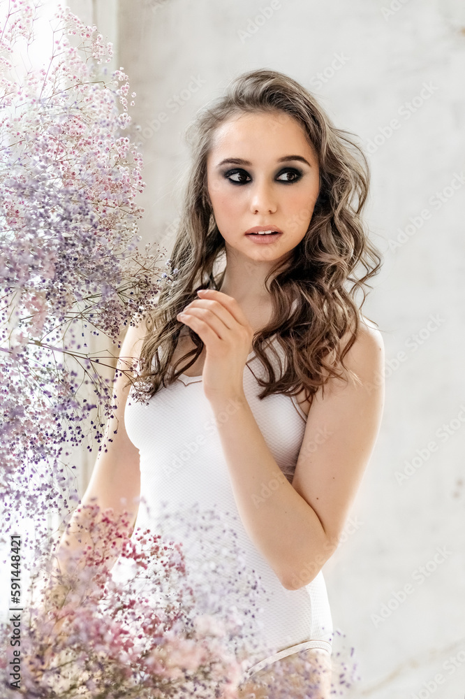 A beautiful romantic young woman with makeup poses against a background of colorful gypsophila flowers. The concept of perfumery, cosmetics.Spring A beautiful romantic young woman with makeup poses against a background of colorful gypsophila flowers. The concept of perfumery, cosmetics.Spring