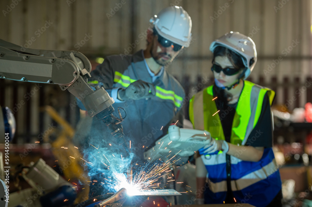 Engineer control robot arm machine welding steel, worker using forcing welding control screen which for precision welding control. Worker control automation welding robot in hi tech heavy factory Engineer control robot arm machine welding steel, worker using forcing welding control screen which for precision welding control. Worker control automation welding robot in hi tech heavy factory
