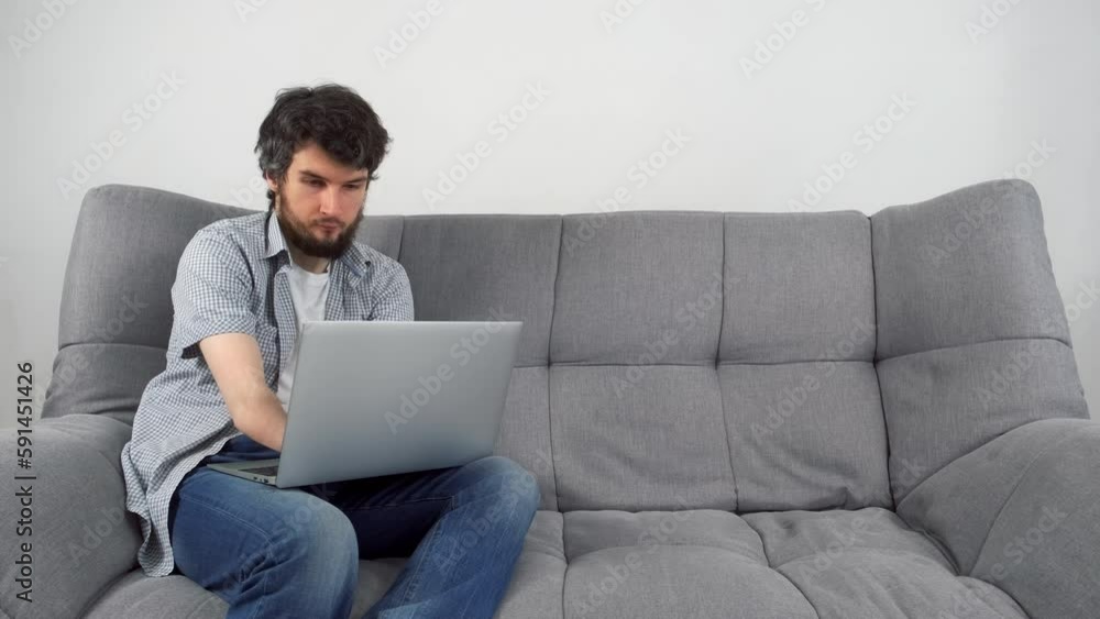 Handicapped Disabled man with amputated two stump hands working typing on laptop at home office sitting on sofa. Problem adaptation to life people with disabilities. Independent Invalid person. Handicapped Disabled man with amputated two stump hands working typing on laptop at home office sitting on sofa. Problem adaptation to life people with disabilities. Independent Invalid person.