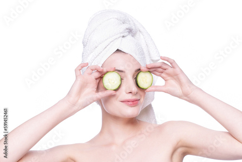 Beautiful woman with clean fresh skin smiles applying cream with two cocumbers on eyes. Gherkin care treatment. Natural healthy cosmetic smiling portrait. Cosmetology, beauty, spa