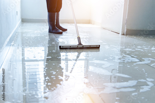 Janitor squeegee water on the floor hallway office building or walkway after school and classroom work job with sun light background. Wet floor or cleaning service house maid concept. photo