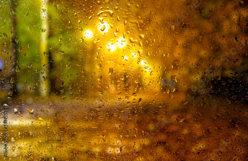 City view through a window on a rainy night,Rain drops on window with road light bokeh, City life in night in rainy season abstract background. Focus on drops on glass © Павел Мещеряков