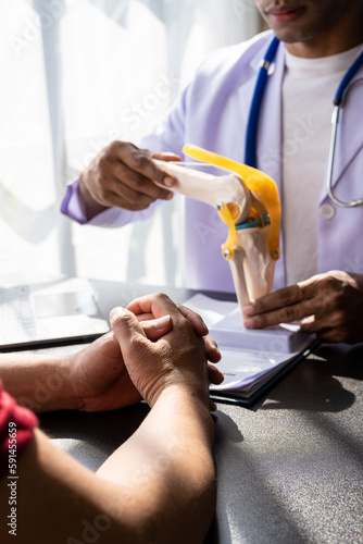 Physical therapist showing knee model to male patient during consultation at doctor's office medical appointments and treatments