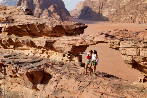 close view of two tourists on rocks visiting wadi rum desert photo
