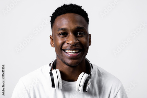 Portrait close up shot of delighted african american man guy black in white t-shirt wearing new modern white headphones earhones looking at camera smiling. photo