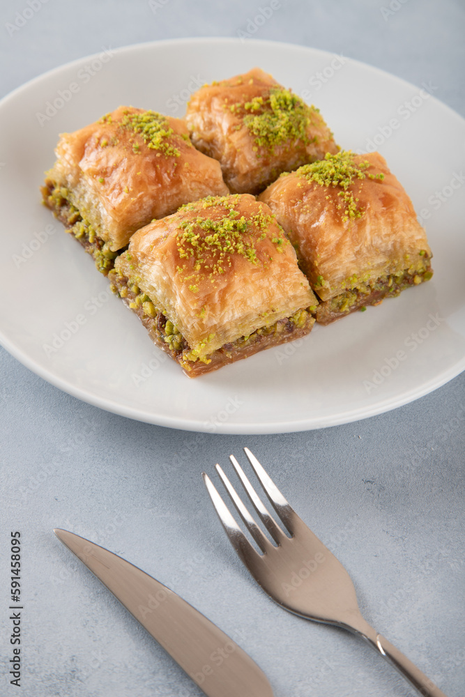 Pistachio Turkish baklava on a white plate.Close-up of four slices of baklava
