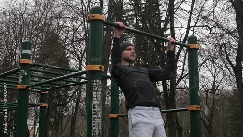 Wallpaper Mural a guy performs a pull-up exercise on a horizontal bar on a sports field on the street, a man does sports, slow motion Torontodigital.ca