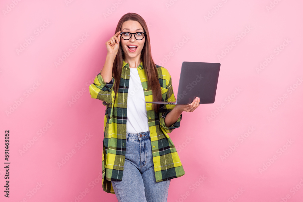 Portrait of funny impressed girl with straight hairdo wear plaid shirt hold laptop touch glasses isolated on pink color background Portrait of funny impressed girl with straight hairdo wear plaid shirt hold laptop touch glasses isolated on pink color background