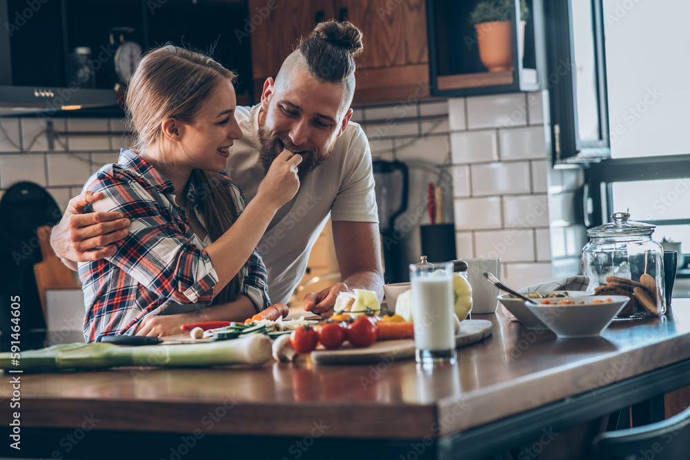 Young couple preparing a meal in their kitchen.
Young couple preparing a meal in their kitchen.