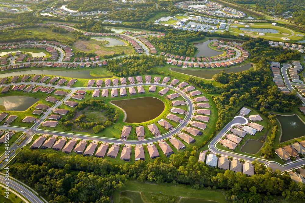 Aerial view of tightly located family houses with retention ponds to prevent flooding in Florida closed suburban area. Real estate development in american suburbs