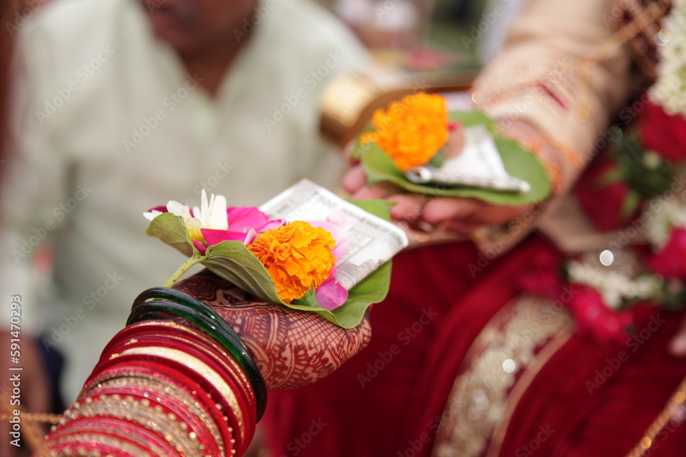 Indian marriage ritual, focus on Bride holding a leaf containing flowers , betel nut and money