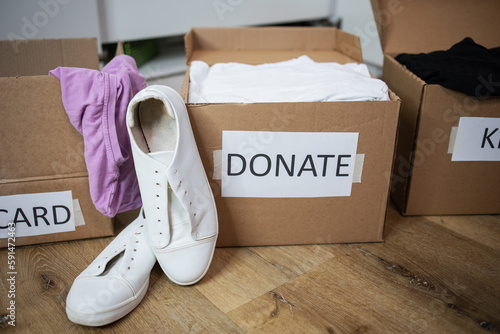 Close up clothes being sorted into of boxes Keep, Discard, Donate categories white sneaker. Zero Waste, recycling, sustainable. Decluttering and aleaning up closet or wardrobe photo