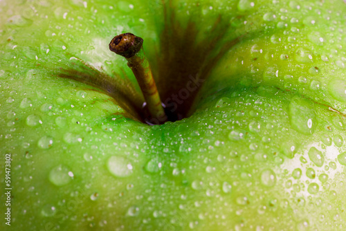 Green apple with dew drops on the peel close-up.