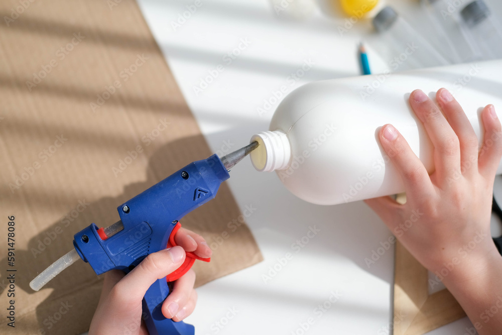 Step-by-step instructions for making crafts from improvised materials. Handmade at school craft rocket for the day of cosmonautics. A child smears a plastic bottle with glue. Step 2