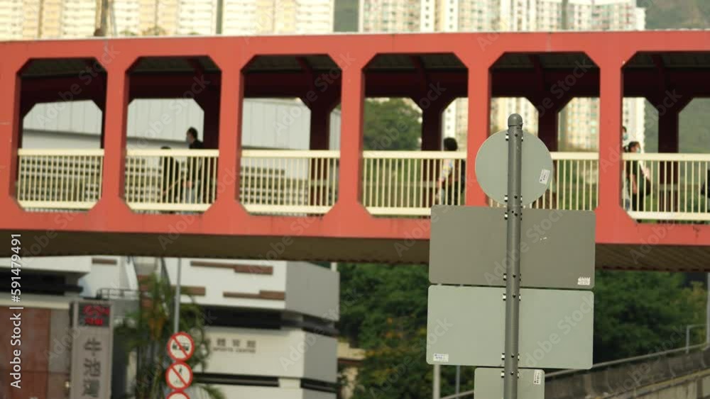 People walking on a pedestrian bridge over a busy street in Hong Kong People walking on a pedestrian bridge over a busy street in Hong Kong