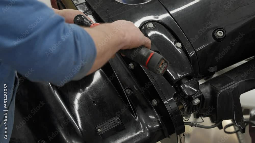 mechanic using an electric drill to repair a boat motor mechanic using an electric drill to repair a boat motor