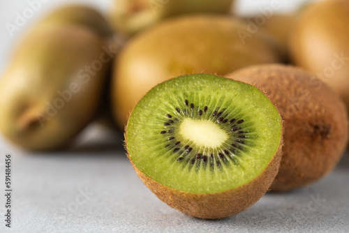 Green ripe kiwi half and whole on grey table. Place for text. Horizontal photo.