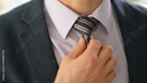 Businessman manager in suit straightening tie on shirt in office closeup. Business elegant style concept