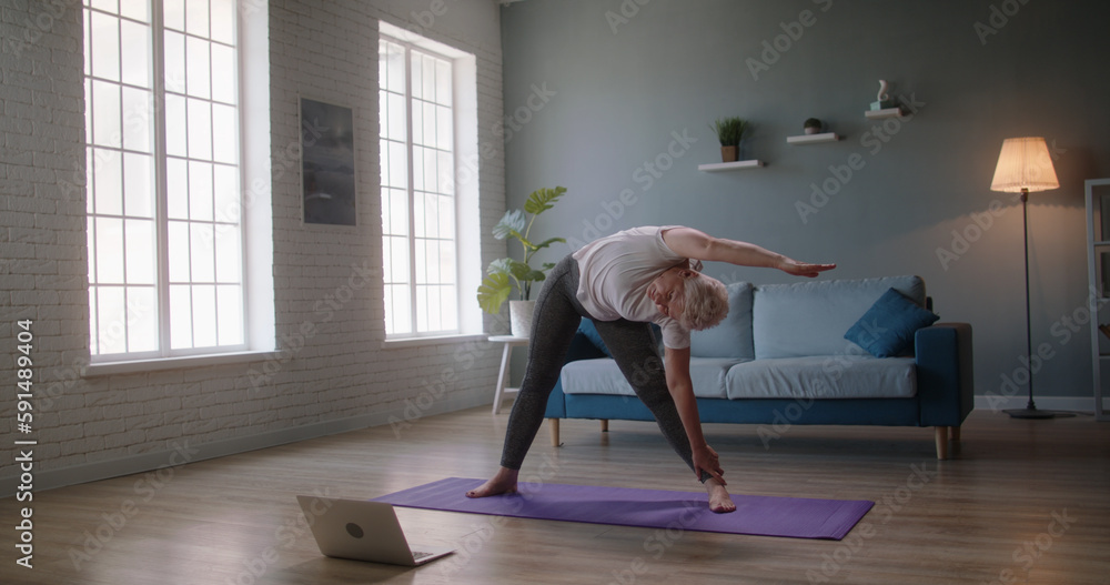 Senior fit caucasian woman doing pilates. Mature athlete exercising and stretching, doing yoga, keeping a healthy lifestyle - wellness 