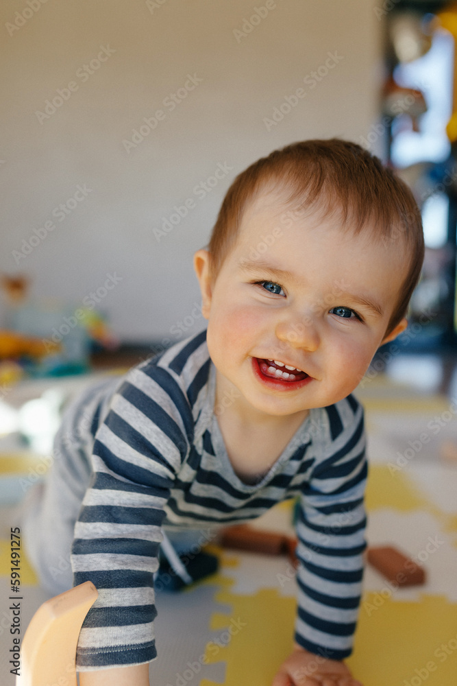 Close up portrait of spectacular lovely little boy with wonderful smile I posing to camera while playing in his room with toys. happy little kids in striped suit smiling and enjoying time. Close up portrait of spectacular lovely little boy with wonderful smile I posing to camera while playing in his room with toys. happy little kids in striped suit smiling and enjoying time.
