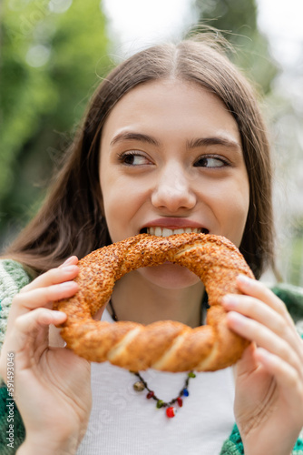 Young woman biting turkish simit bread outdoors in Istanbul.