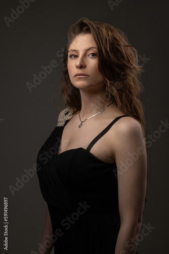 studio portrait of a latin woman with long hair with serious expression, wears a formal dress and necklace as an accessory, beauty and fashion