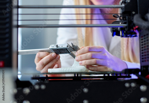 Hands of woman using vernier calliper at 3D printing machine in laboratory photo