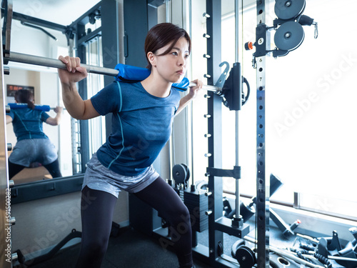 パワーラックでスクワットする女性