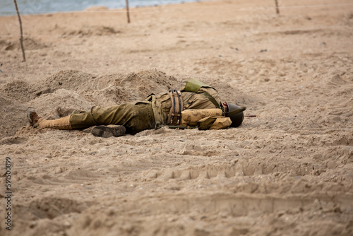 Historical reconstruction. Injured or dead World War II infantry  soldier  on the beach. View from the back.  Hel, Poland