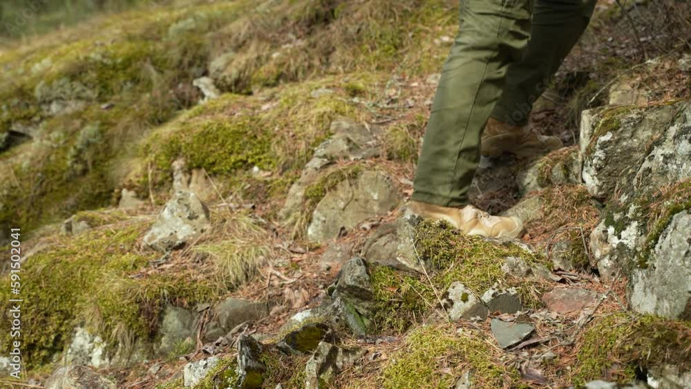 View of the travellers feet in trekking boots climbing up the forest slope. View of the travellers feet in trekking boots climbing up the forest slope.