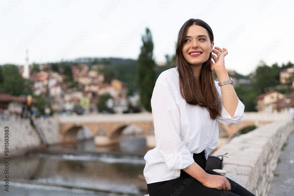 The young woman sits on the stone wall in the old town