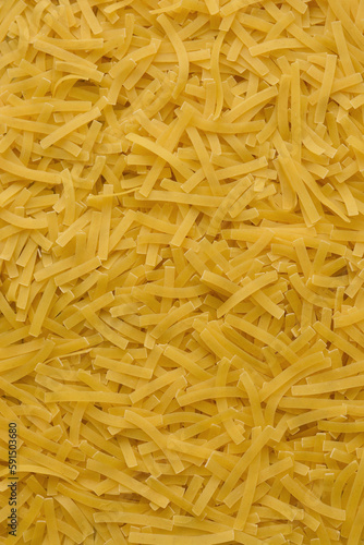 Yellow background with raw vermicelli noodles. Concept - pasta as background.