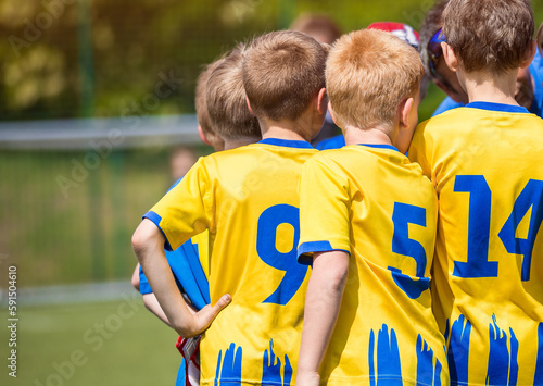 Boys motivating each other in sports team before the football tournament match. Soccer kids with the coach. Portrait of a friendly football team gathered together with the coach