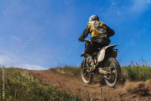 motocross rider riding off-road motorcycle racing trail, ground and dust from under rear wheel