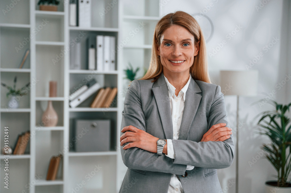 Standing with arms crossed. Woman in business formal clothes is working in office Standing with arms crossed. Woman in business formal clothes is working in office
