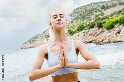 Portrait of a sporty woman during meditation on the background of the sea. Healthy lifestyle and peace of mind. © makedonski2015