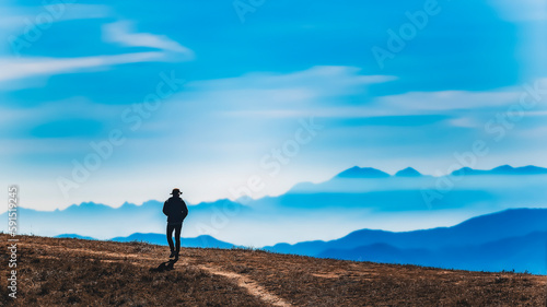 A Tourist enjoying with fog in Chiangmai, Thailand. A man on the mountain with beautiful fog. The Beautiful Morning Time. Travel and tourism. Young man on the peak of the mountain with morning fog 