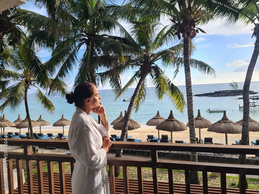 Happy woman with hands raised to sky looking at ocean on a paradise island Happy woman with hands raised to sky looking at ocean on a paradise island