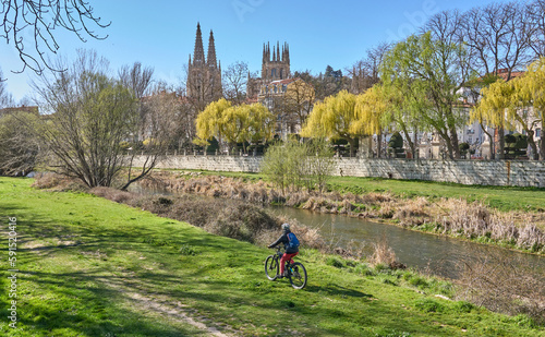 nice woman cycling with her electric bicycle at the banks of Rio Arlazon in Burgos, Castile-Leon, Spain photo