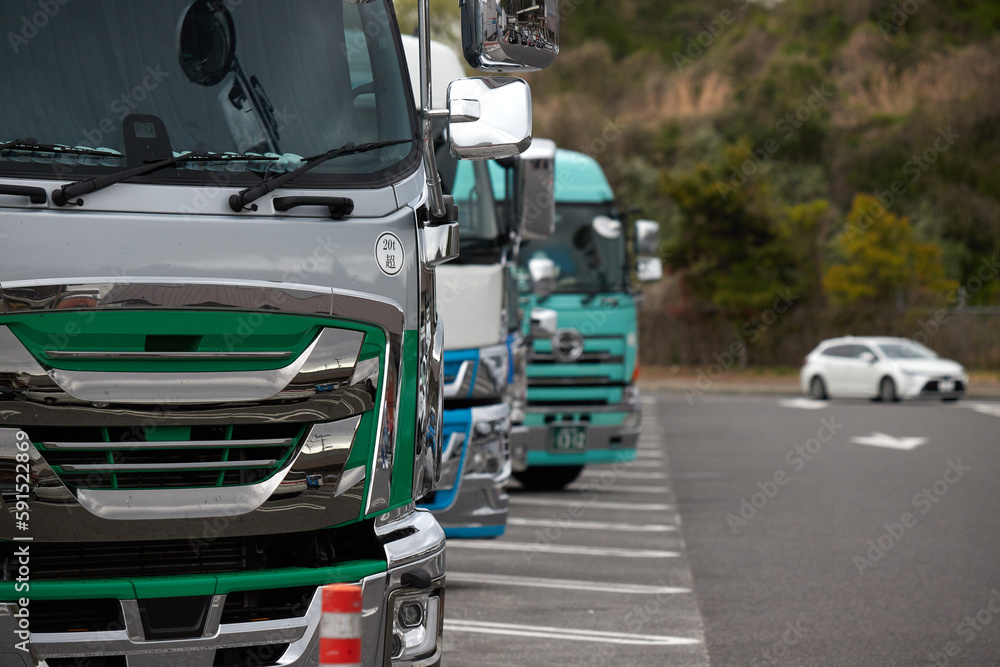 高速道路のサービスエリアの駐車場に並ぶ大型トラックの風景