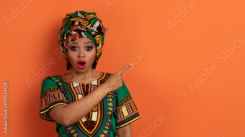 Shocked black woman in african clothes showing copy space